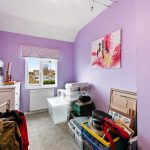 Small purple room with clutter and window view.