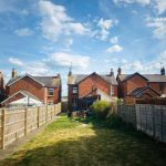 Back garden view of red brick houses.