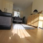 Modern living room with sunlight on wooden floor.