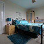Bright bedroom with turquoise decor and wooden furniture.