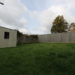 Back garden with grass and wooden fence.