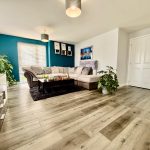 Modern living room with teal accent wall and plants.