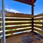 Wooden balcony with garden view on sunny day.