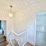 Bright hallway with staircase and bathroom entrance.