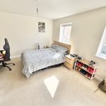 Bright bedroom with bed, desk, and shoe rack.