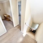 Carpeted hallway and stairway inside a house