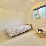Minimalist bedroom with single bed and chair.