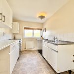 Spacious modern kitchen with white cabinets and window.
