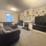 Cosy living room with floral wallpaper and large sofa.