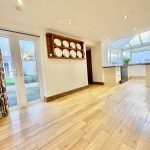 Spacious kitchen with wooden flooring and glass doors.
