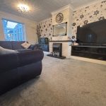 Cosy living room with large TV and fireplace.